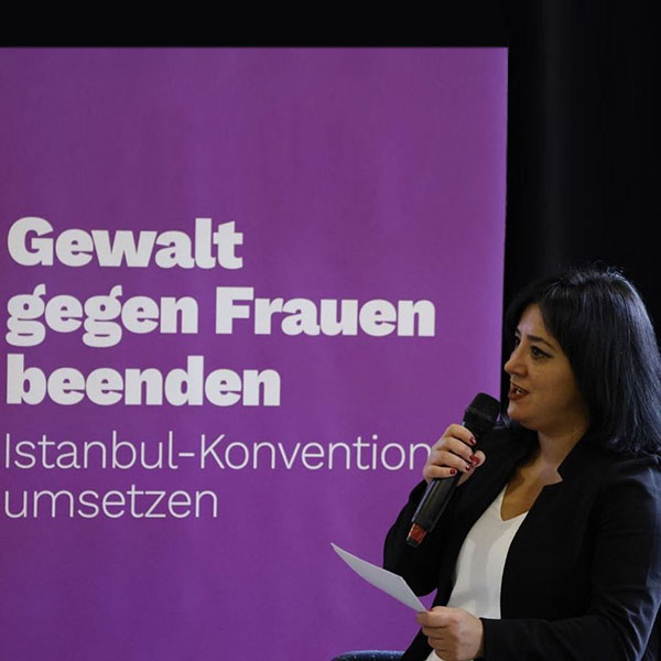 Gökay Akbulut spricht vor einem Banner mit Aufschrift "Gewalt gegen Frauen beendet - Istanbul-Konvetion umsetzen"